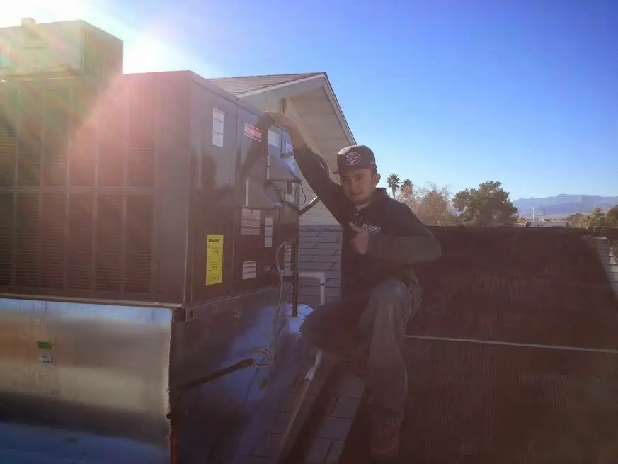 HVAC technician performing Air Duct Cleaning on a rooftop unit in Newington
